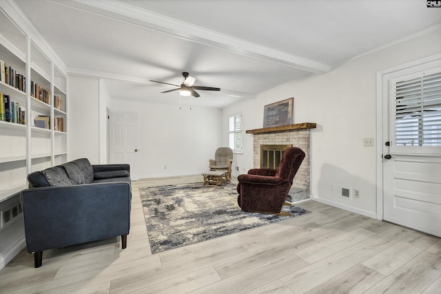 living room with visible vents, a ceiling fan, ornamental molding, light wood-style floors, and a fireplace