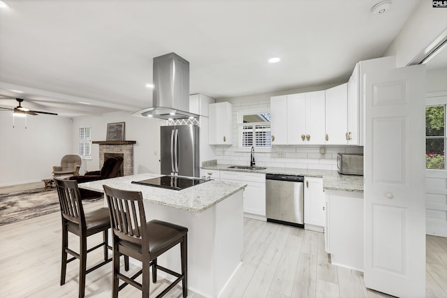 kitchen featuring ventilation hood, backsplash, a sink, a center island, and appliances with stainless steel finishes