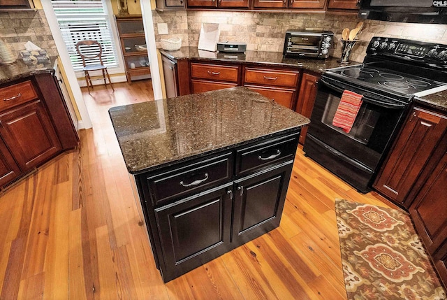 1437 Heins Rd, Blythewood, SC 29016 - kitchen featuring dark stone counters, light wood finished floors, backsplash, a kitchen island, and electric range