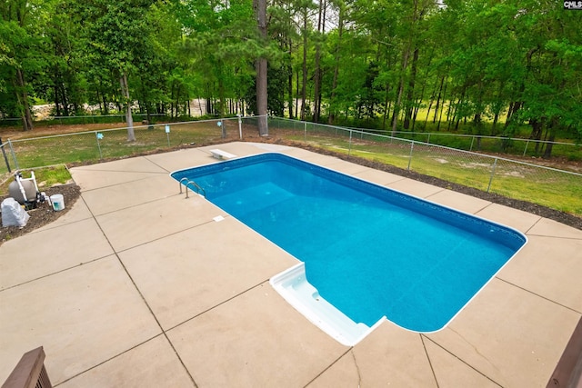 pool with a patio area, fence, and a diving board