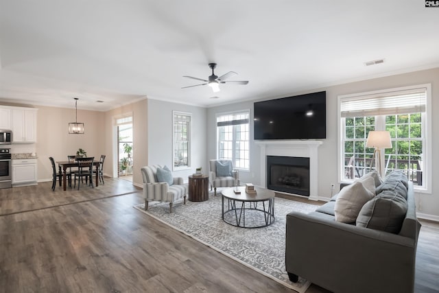 living area featuring wood finished floors, crown molding, and plenty of natural light