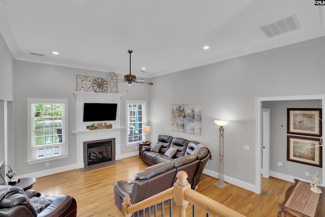 living room featuring a fireplace with flush hearth, visible vents, and light wood-type flooring