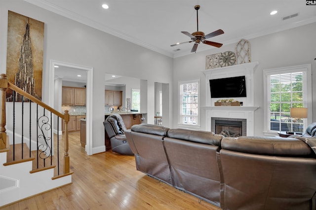 living area featuring light wood-type flooring, a ceiling fan, a fireplace, and recessed lighting
