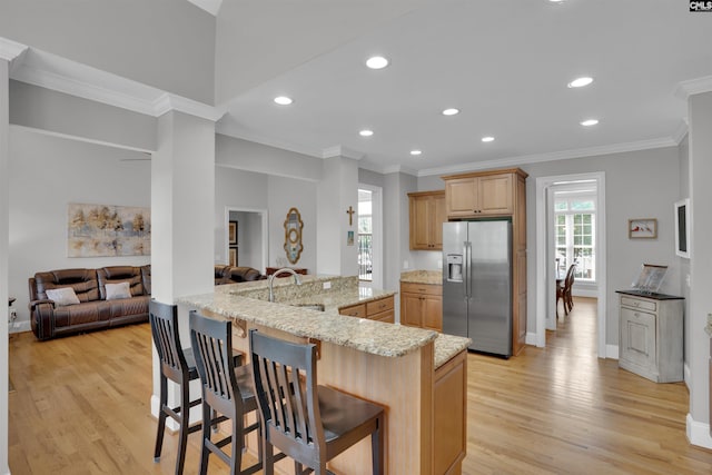 kitchen featuring a sink, a breakfast bar, light wood-type flooring, recessed lighting, and stainless steel refrigerator with ice dispenser
