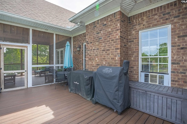 wooden deck featuring a sunroom, outdoor dining space, and a grill