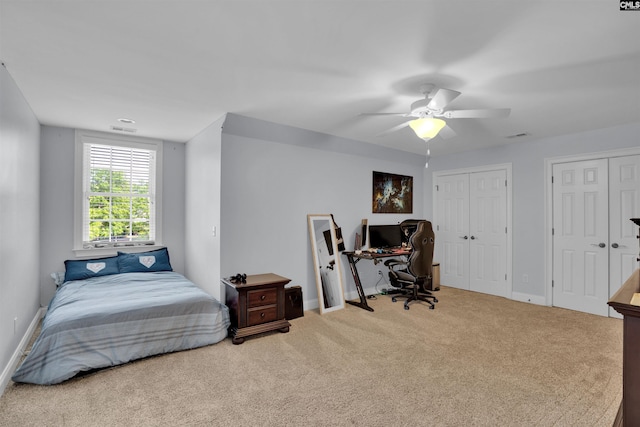 carpeted bedroom featuring a ceiling fan, two closets, visible vents, and baseboards