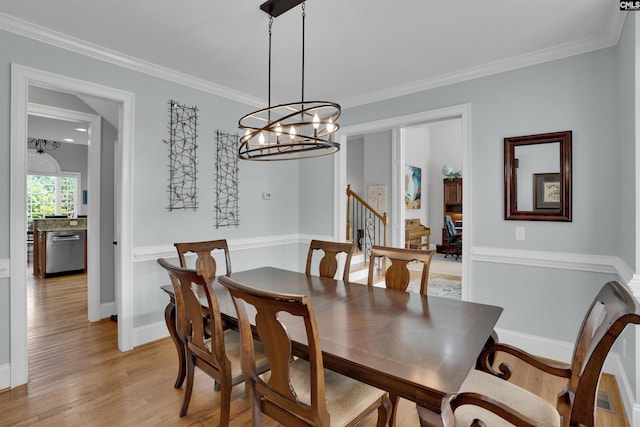 dining space featuring a chandelier, ornamental molding, and light wood-style floors