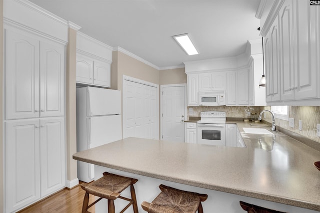 kitchen with a kitchen breakfast bar, white cabinets, a sink, white appliances, and a peninsula