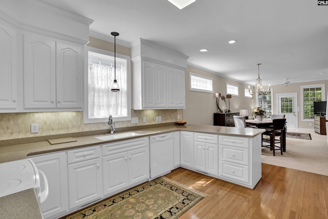 kitchen featuring hanging light fixtures, white dishwasher, a sink, white cabinetry, and light wood-type flooring
