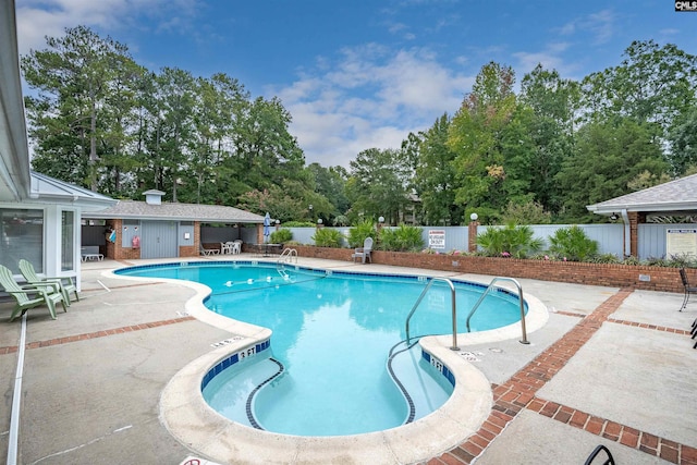 community pool with a patio and fence
