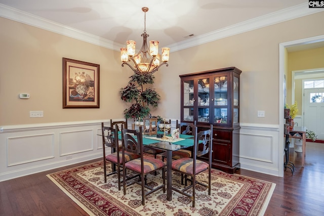 dining room with dark wood finished floors, visible vents, ornamental molding, and an inviting chandelier
