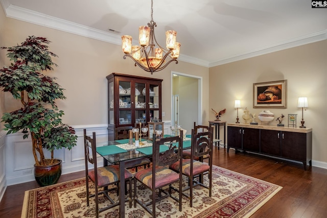 dining space featuring an inviting chandelier, wainscoting, ornamental molding, visible vents, and dark wood-type flooring