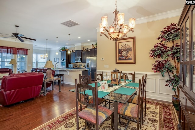dining space featuring ornamental molding, dark wood finished floors, visible vents, and ceiling fan with notable chandelier