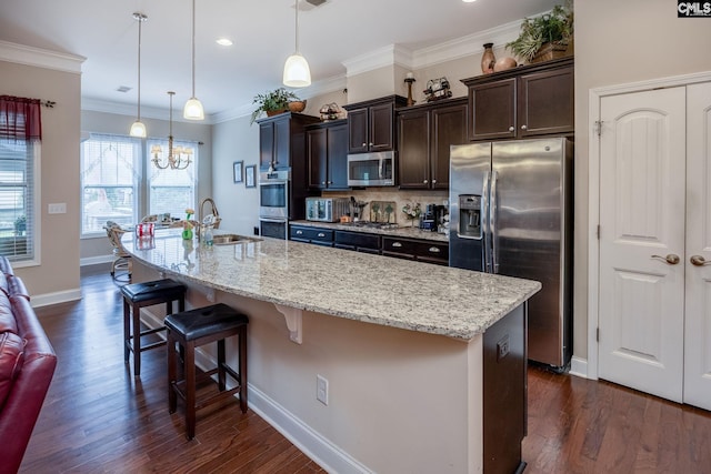 kitchen featuring a sink, a breakfast bar, dark brown cabinetry, a large island with sink, and appliances with stainless steel finishes