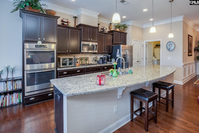 kitchen with a sink, stainless steel appliances, backsplash, a toaster, and dark brown cabinets