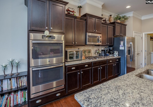 kitchen with a toaster, dark brown cabinets, appliances with stainless steel finishes, and crown molding