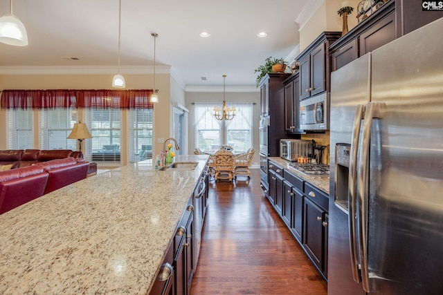 kitchen featuring dark wood-style floors, a sink, stainless steel appliances, a notable chandelier, and light stone counters
