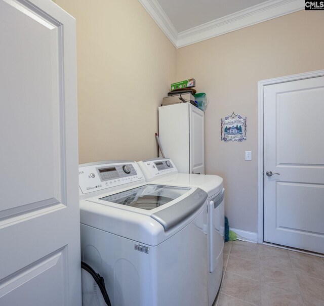 clothes washing area featuring baseboards, light tile patterned flooring, washer and clothes dryer, cabinet space, and ornamental molding