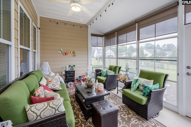 sunroom / solarium featuring a wood stove, an outdoor hangout area, and a ceiling fan