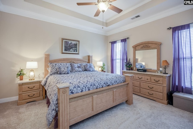 bedroom featuring crown molding, light colored carpet, visible vents, a tray ceiling, and a ceiling fan
