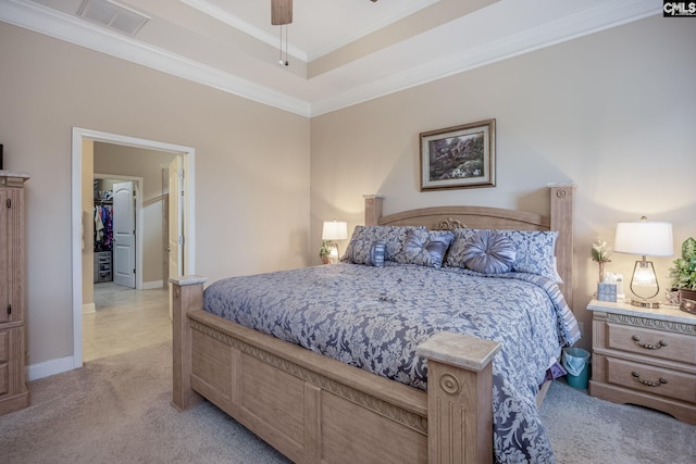 bedroom with a raised ceiling, crown molding, visible vents, light carpet, and baseboards