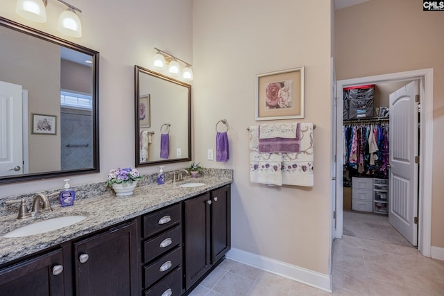 bathroom with tile patterned flooring, a sink, double vanity, and baseboards