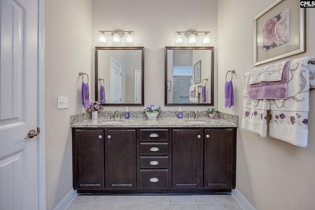 bathroom featuring double vanity, baseboards, tile patterned flooring, and a sink