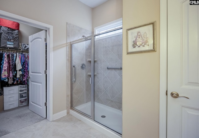 bathroom featuring a stall shower, tile patterned flooring, baseboards, and a spacious closet