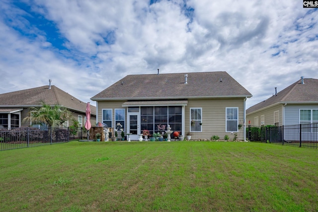 back of property with a fenced backyard, a yard, and a sunroom