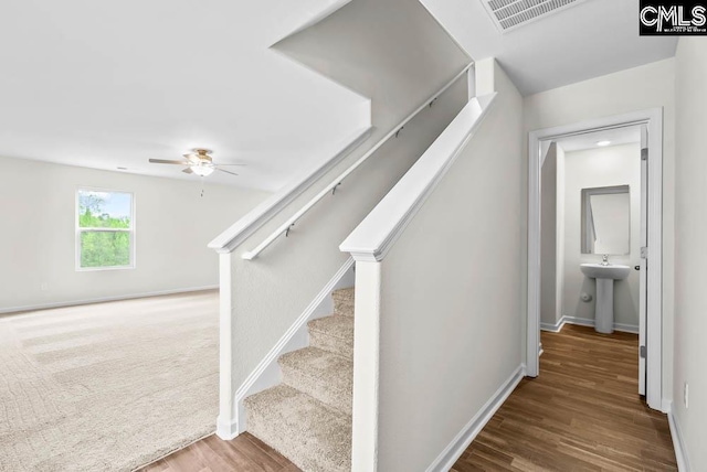 stairway with baseboards, visible vents, wood finished floors, and a ceiling fan