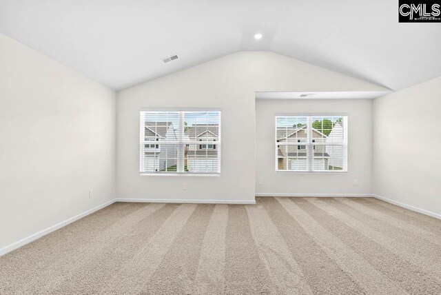 empty room featuring lofted ceiling, carpet, visible vents, and baseboards