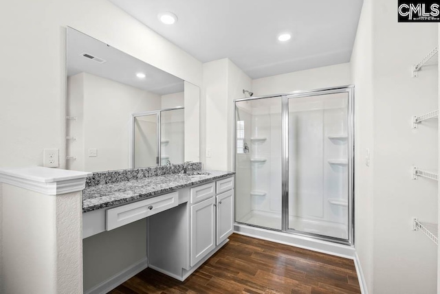 bathroom featuring visible vents, wood finished floors, a shower stall, and vanity