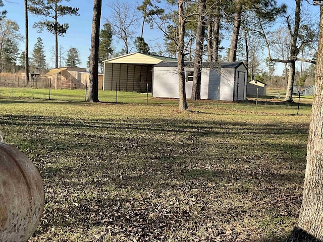 view of yard featuring an outbuilding, a carport, a storage unit, and fence