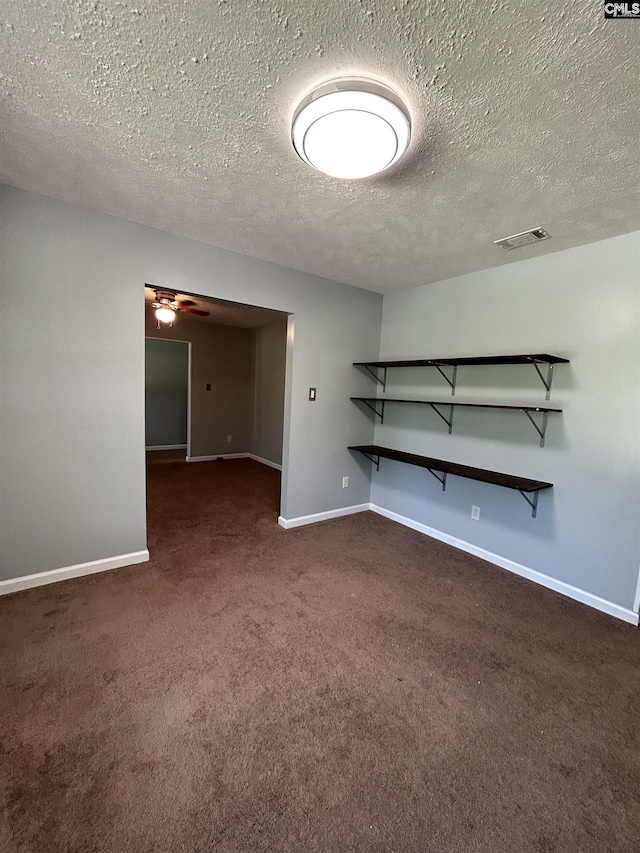interior space with baseboards, dark carpet, and a ceiling fan