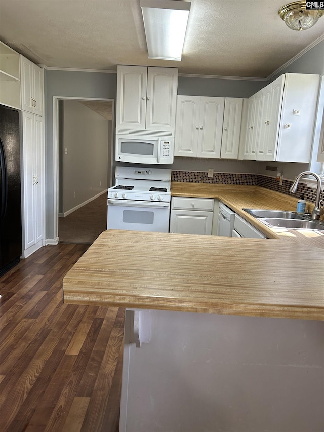 kitchen featuring dark wood finished floors, white appliances, a sink, white cabinetry, and crown molding
