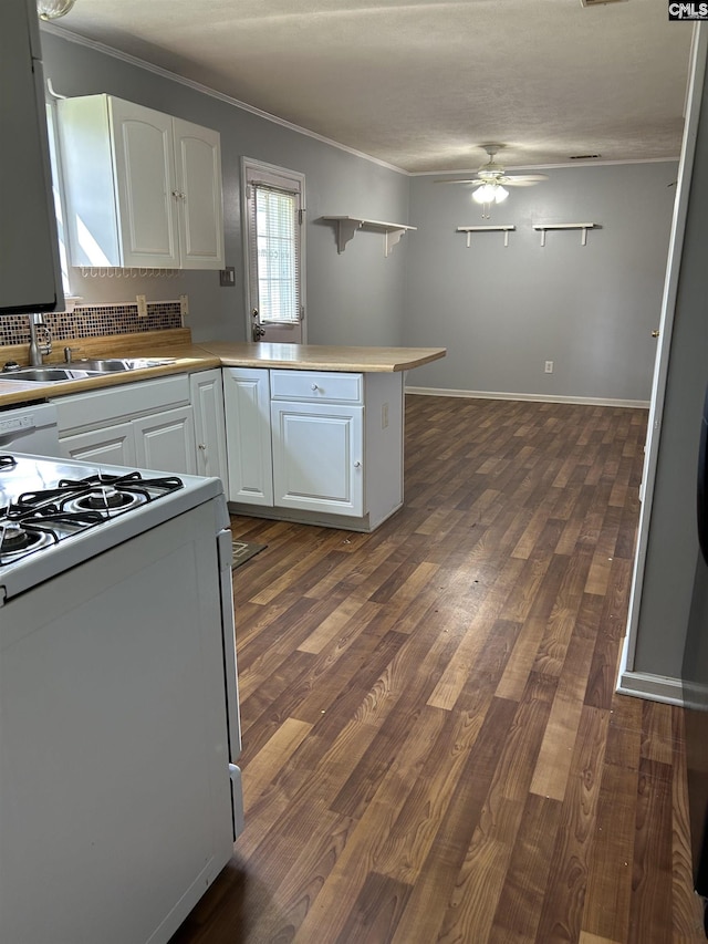 kitchen with white cabinets, ornamental molding, white gas stove, a ceiling fan, and a peninsula