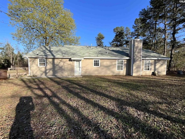 rear view of house with a lawn, fence, a gate, and a chimney
