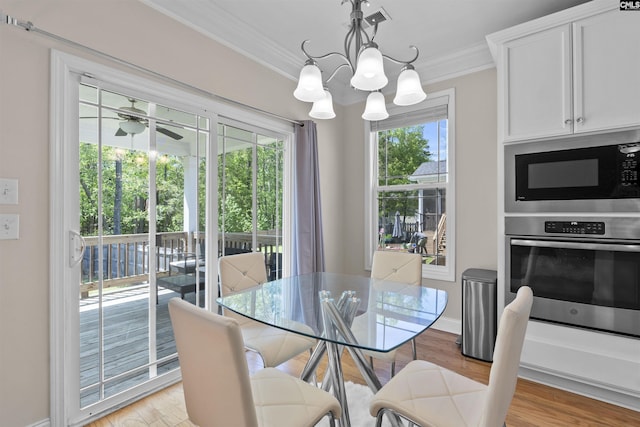 dining room with ceiling fan with notable chandelier, light wood-type flooring, ornamental molding, and baseboards