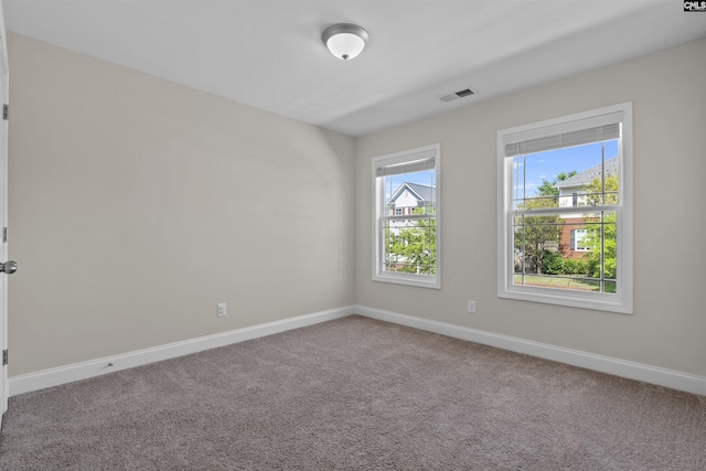 spare room featuring baseboards, visible vents, and carpet flooring
