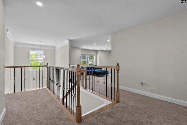 corridor featuring an inviting chandelier, baseboards, carpet, and a healthy amount of sunlight