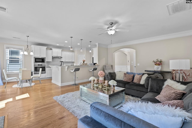 living room featuring visible vents, arched walkways, recessed lighting, ornamental molding, and ceiling fan with notable chandelier