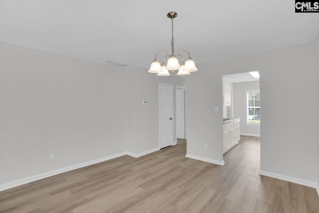 interior space with visible vents, light wood-type flooring, a notable chandelier, and baseboards