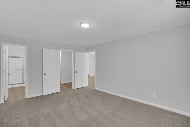 unfurnished bedroom with ornamental molding, carpet flooring, ensuite bath, and baseboards