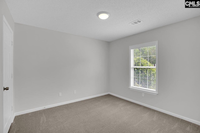 carpeted spare room with baseboards, visible vents, and a textured ceiling