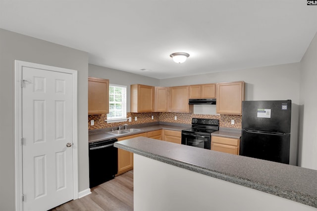 kitchen with under cabinet range hood, tasteful backsplash, light wood-type flooring, black appliances, and light brown cabinetry