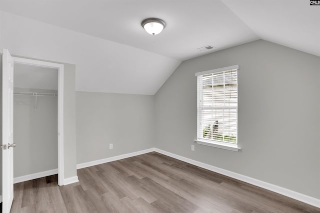 additional living space featuring baseboards, visible vents, wood finished floors, and lofted ceiling