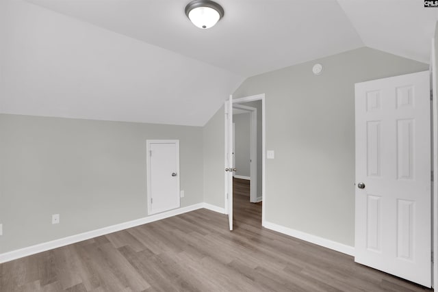 additional living space with wood finished floors, lofted ceiling, and baseboards