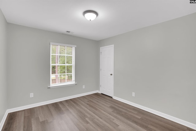 spare room with dark wood-style floors, visible vents, and baseboards