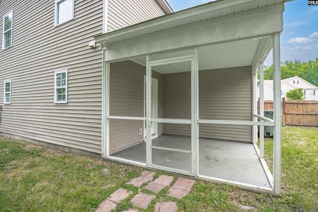 view of home's exterior with a sunroom, a patio, a lawn, and fence