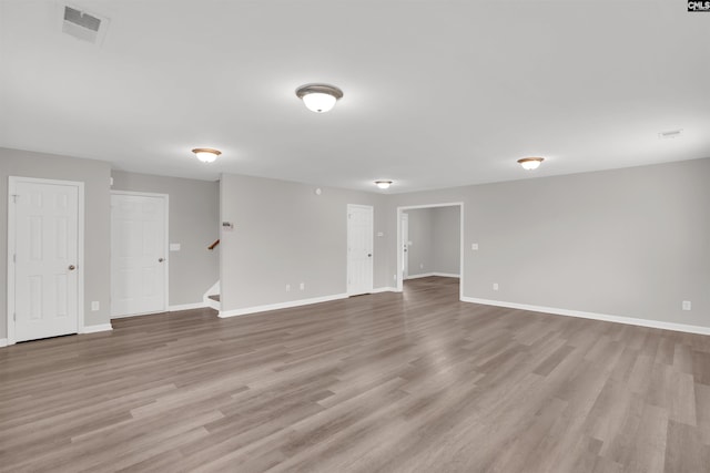 unfurnished room with stairway, visible vents, and baseboards